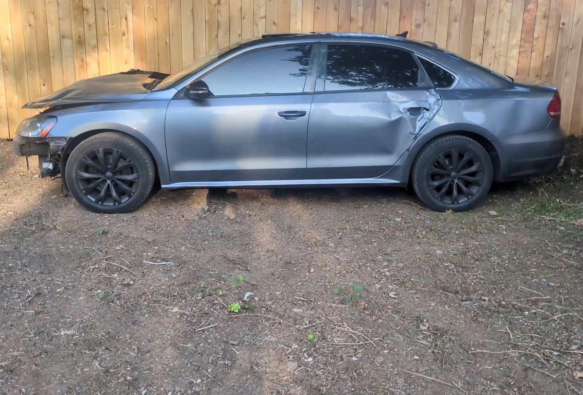 Wrecked grey sedan with front-end and door damage