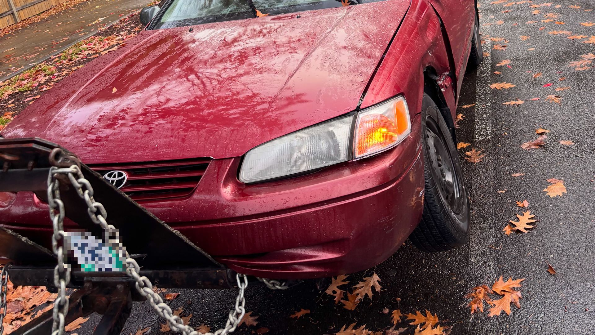 Red Toyota Camry chained to a tow truck, ready to haul